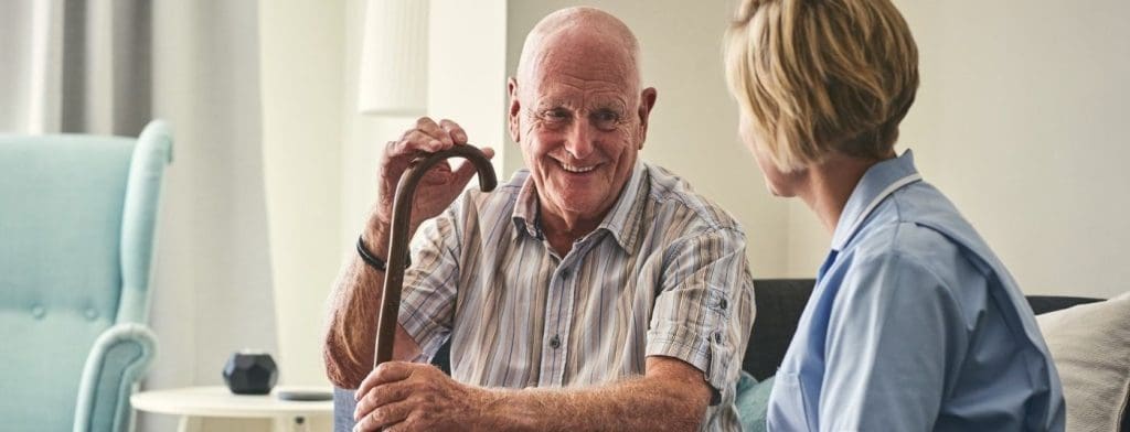 elderly man with cane sitting with nurse