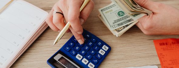 person holding cash using calculator