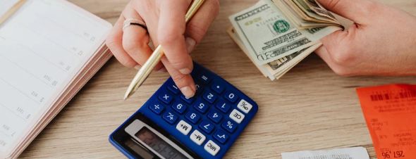 person with cash using calculator